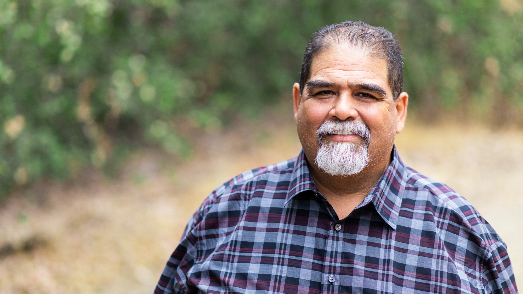 man with grey beard flannel shirt outside