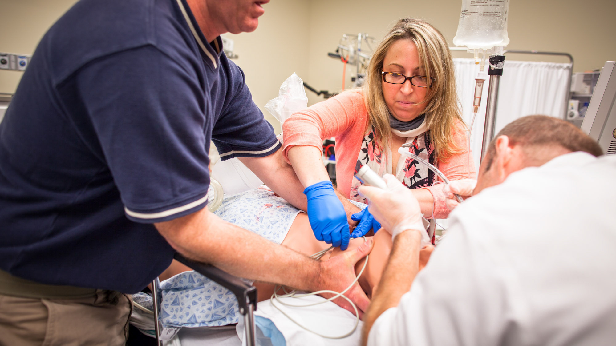 many clinician with hands on a patient on the operating table