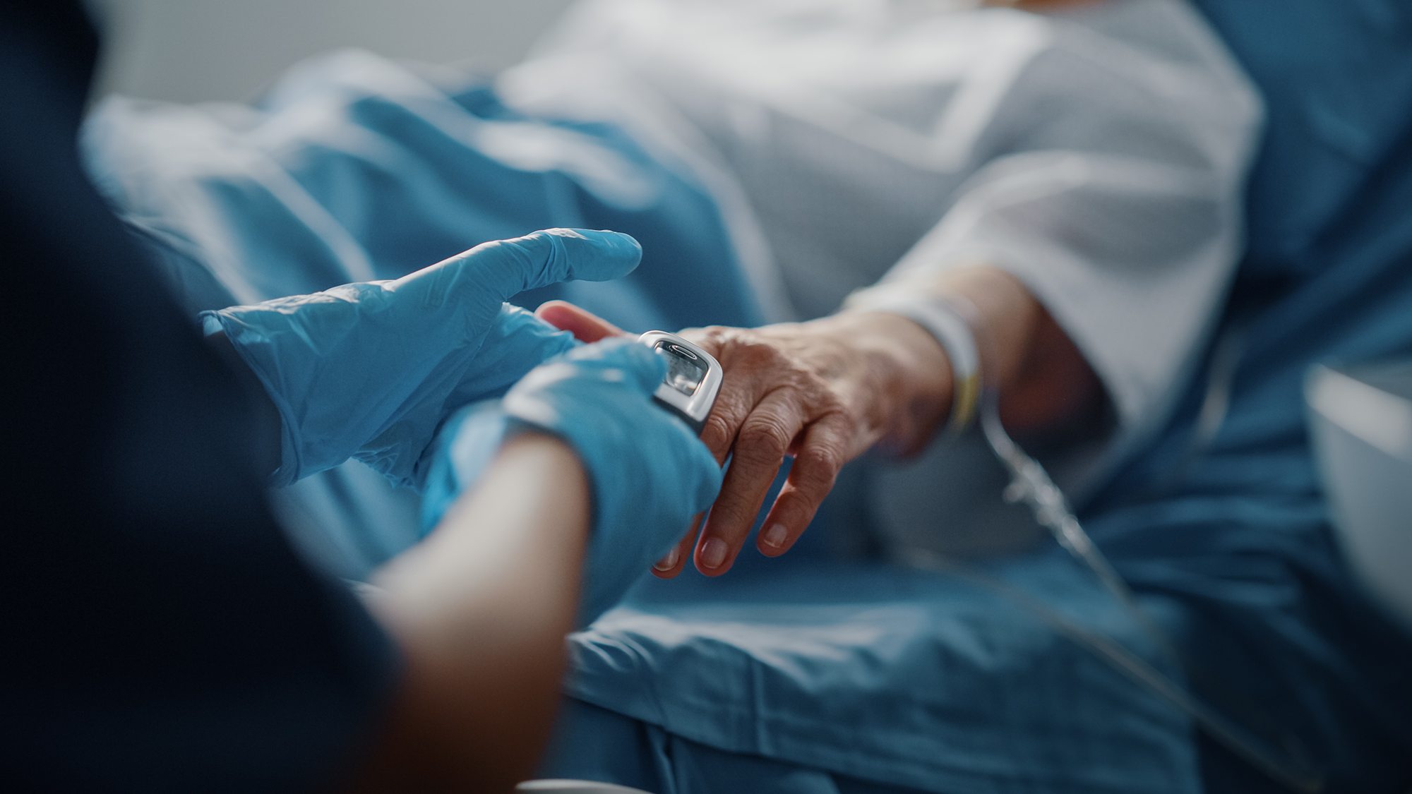 Closeup of a clinician attaching a pulse oximeter to a patient's hand