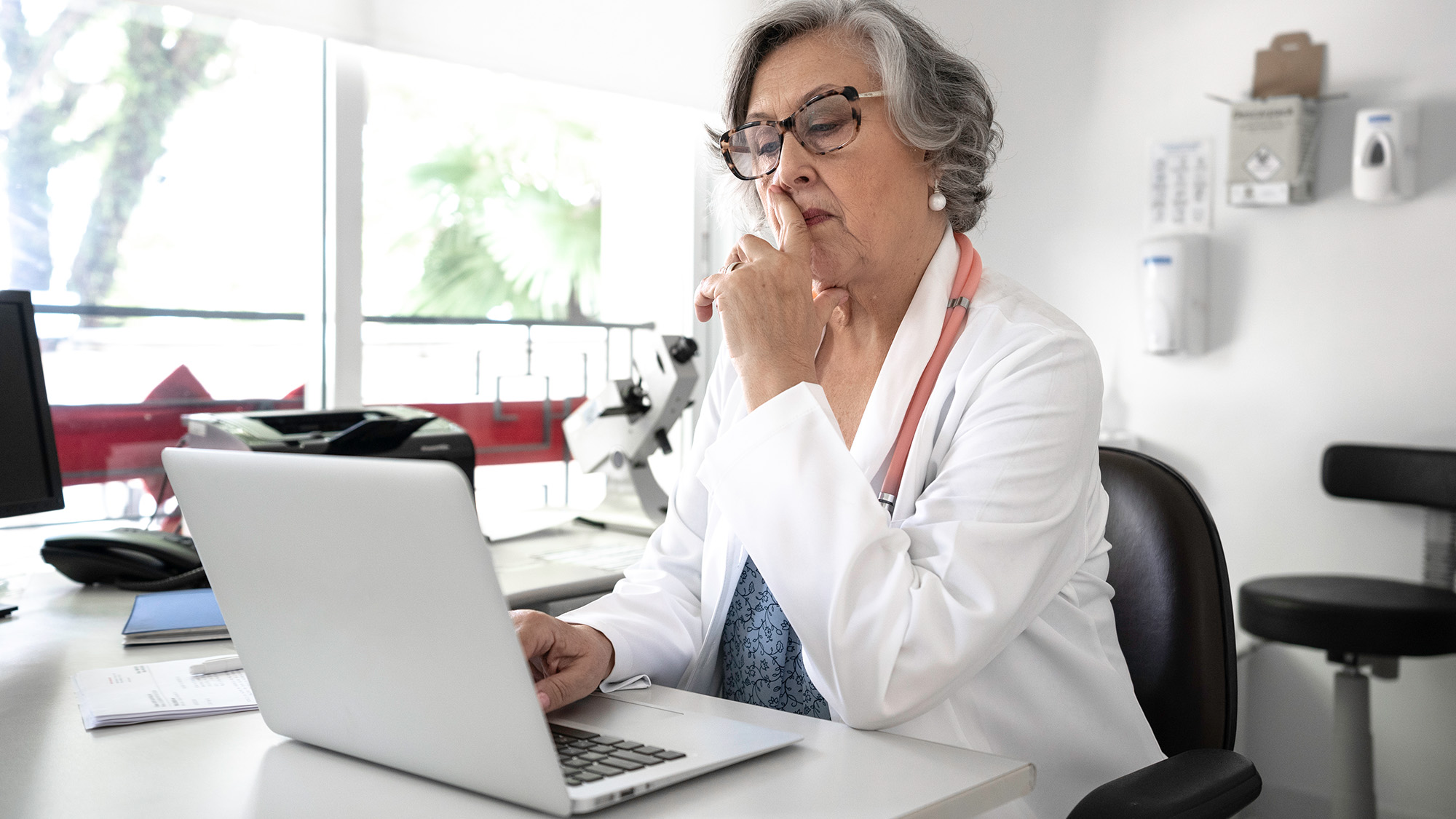 physician looking at a laptop pensively
