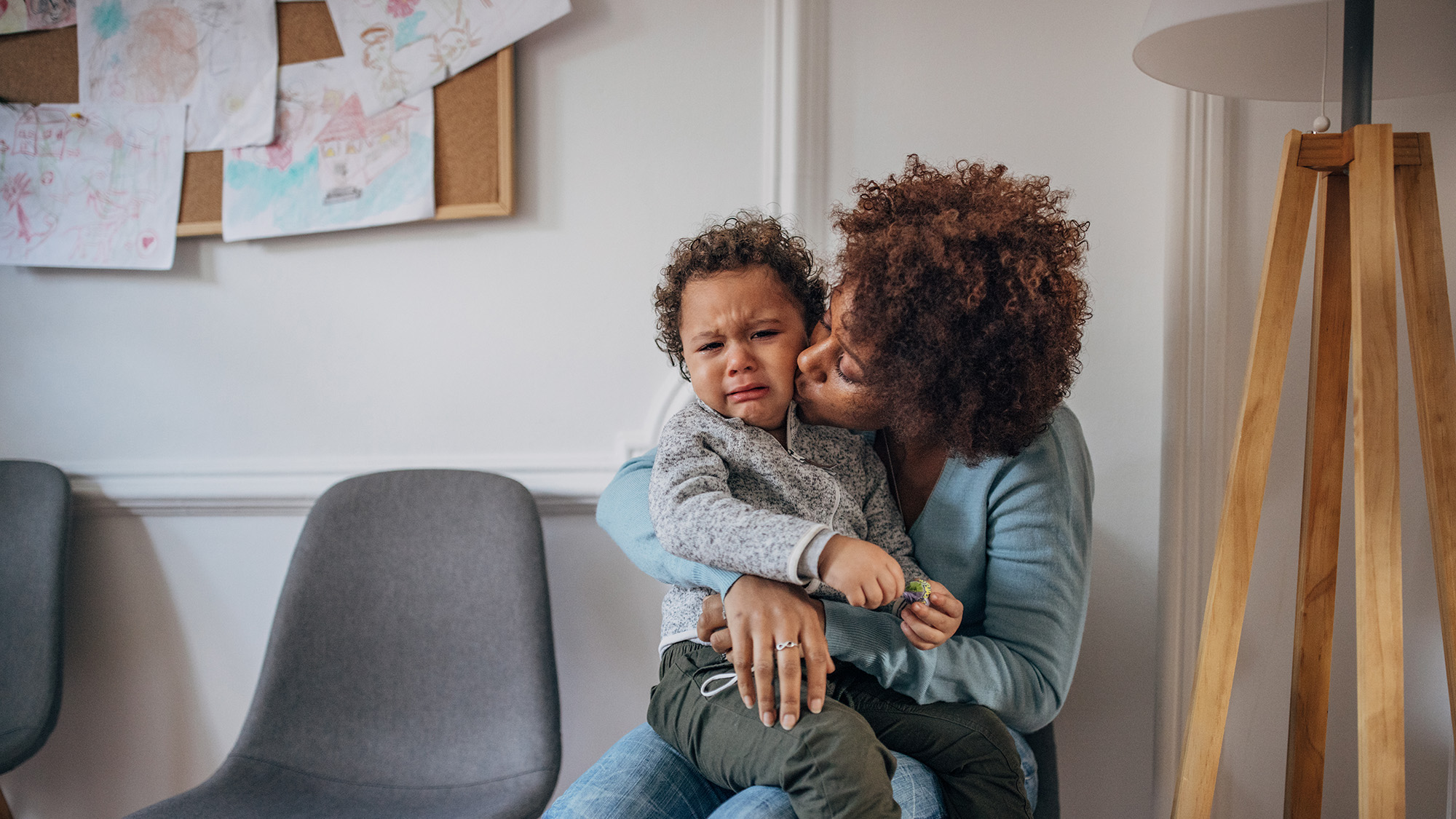 mother comforting crying toddler in waiting room