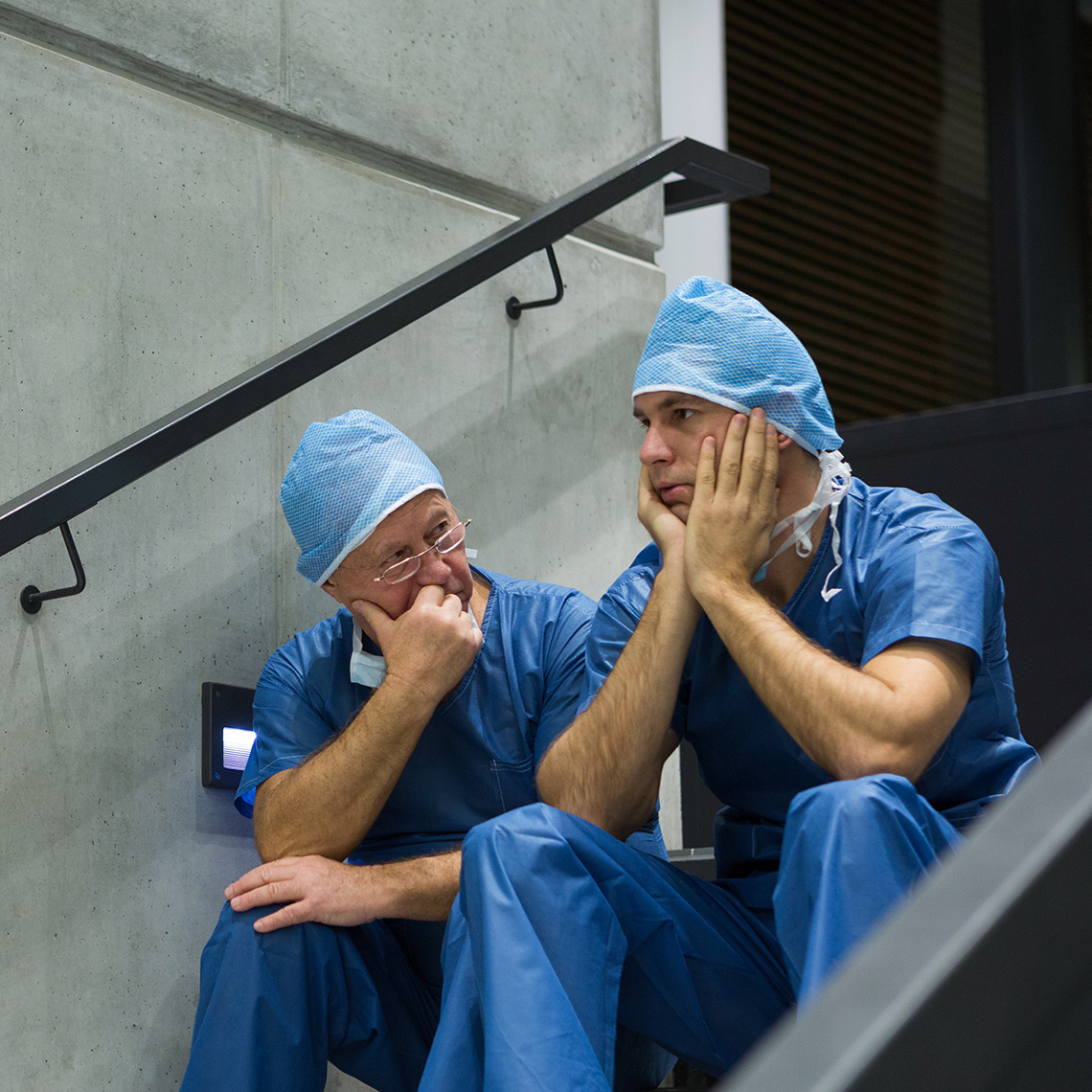 two physicians sitting in a stairwell talking