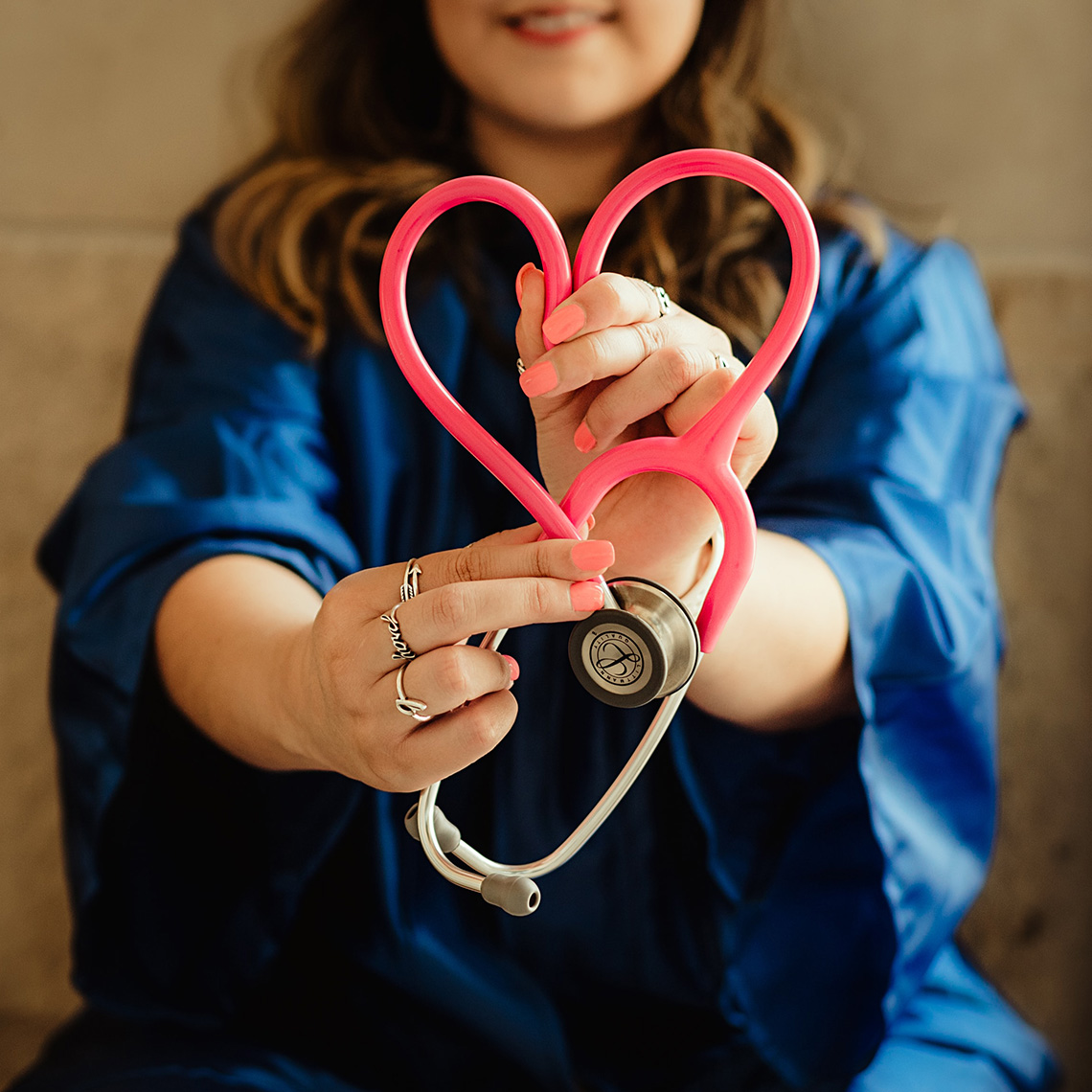 clinician holding a stethoscope in the shape of a heart