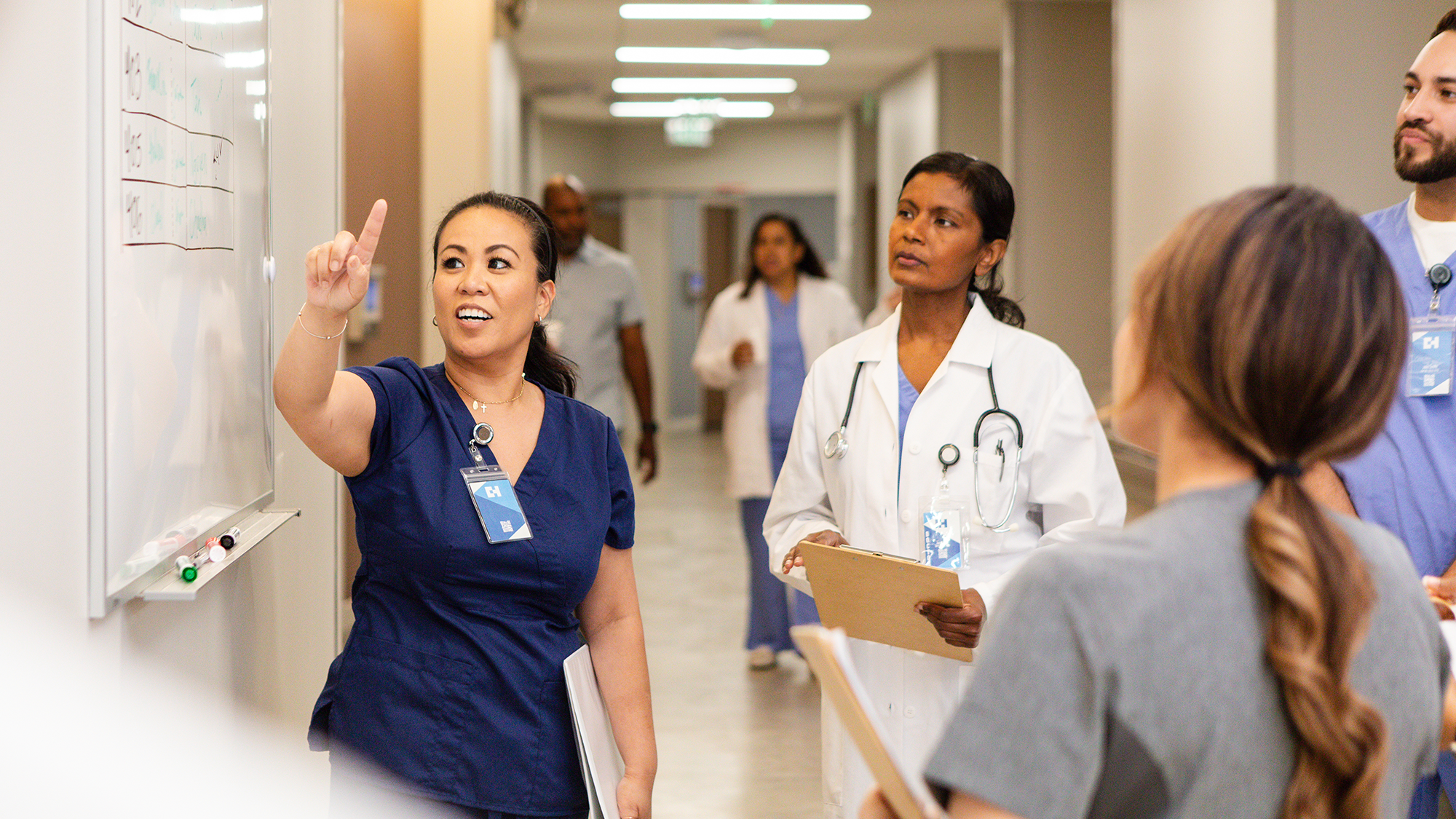 A nurse leads a check-in standing meeting with other clinicians