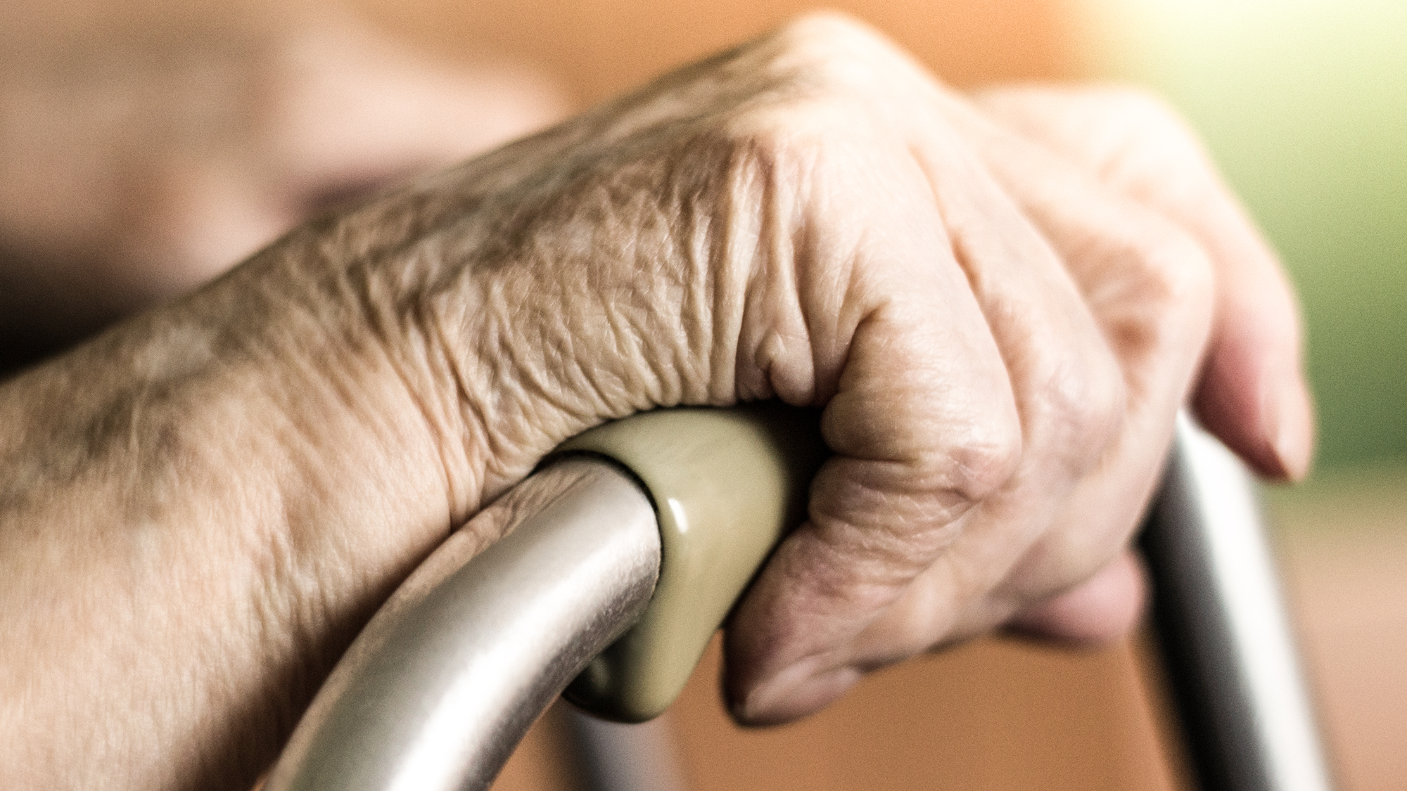 elderly person's hands clasping a walker