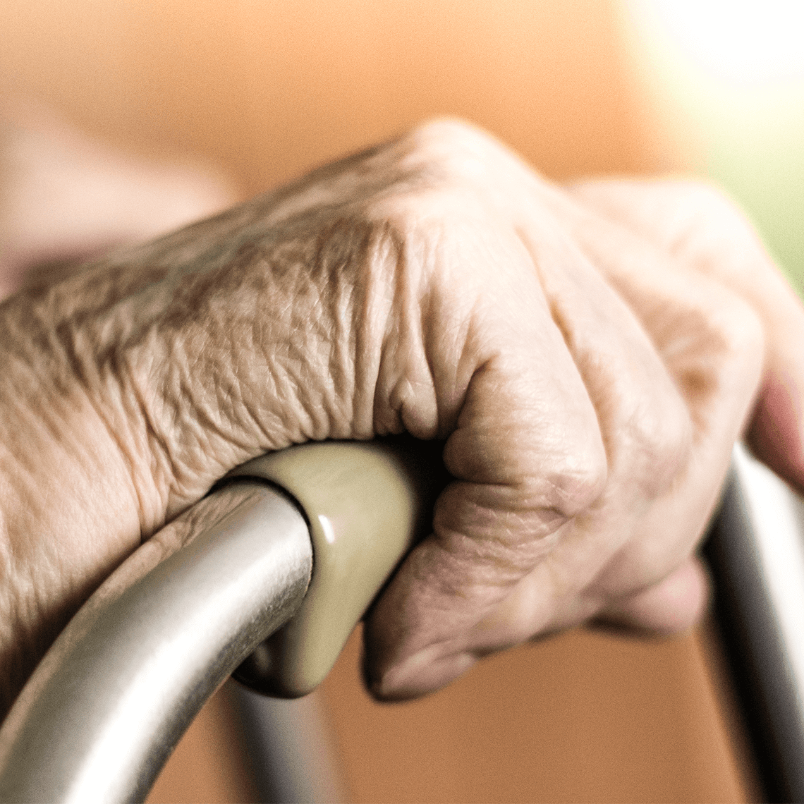 elderly person's hands clasping a walker