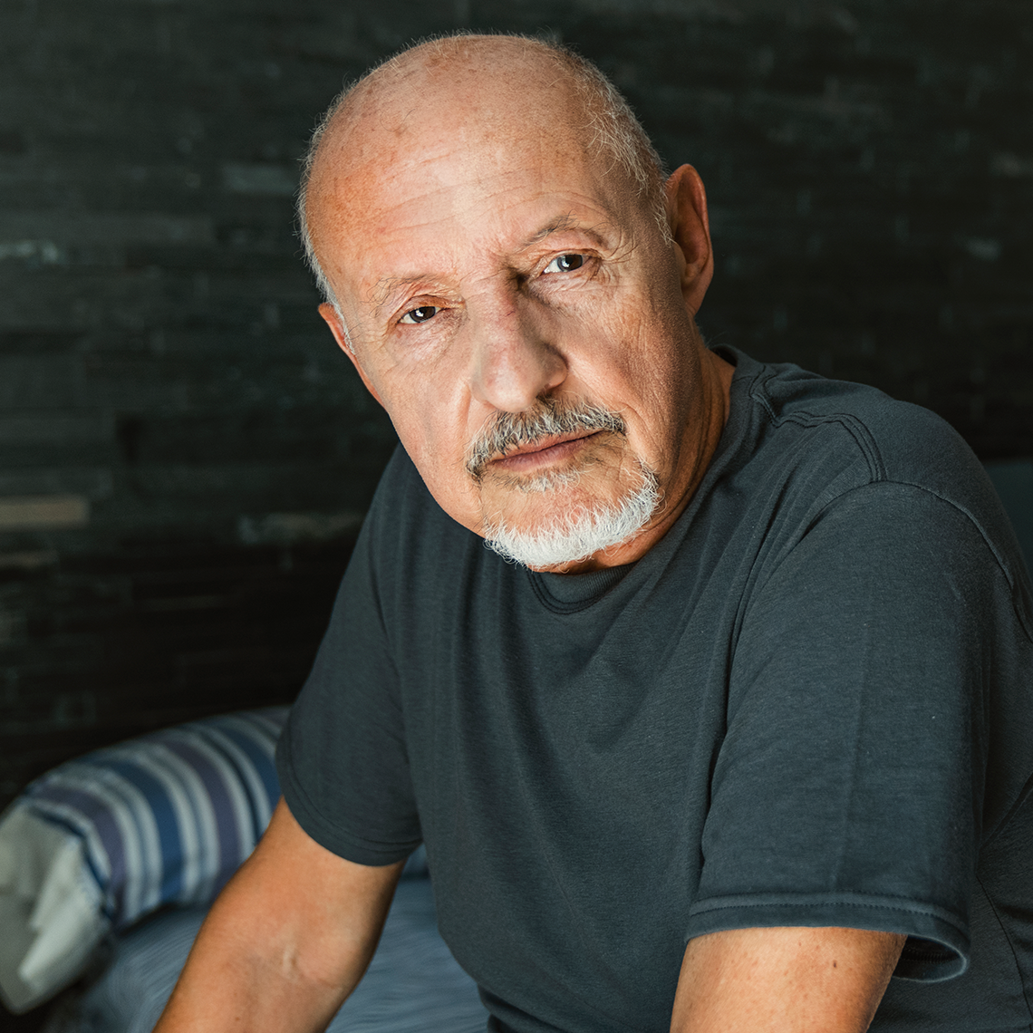 Older man sitting on a bed