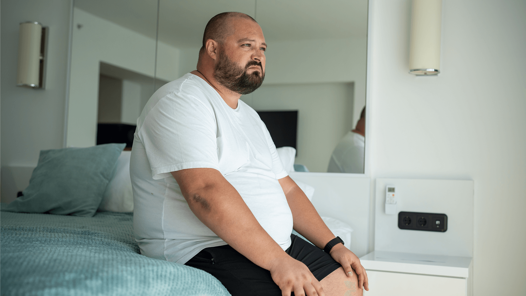 Obese man sitting on a bed