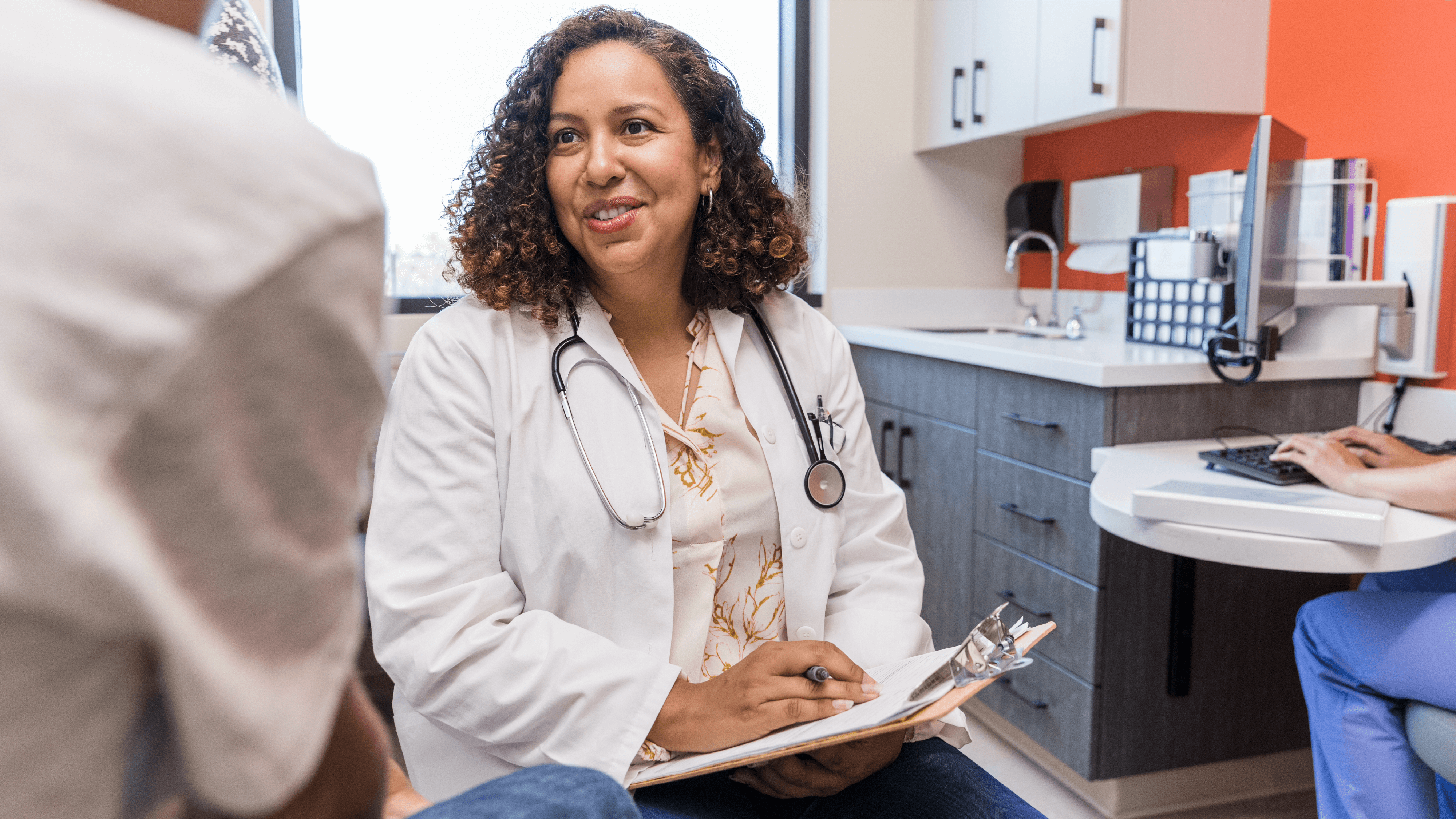 A physician in an exam room talking with a patient