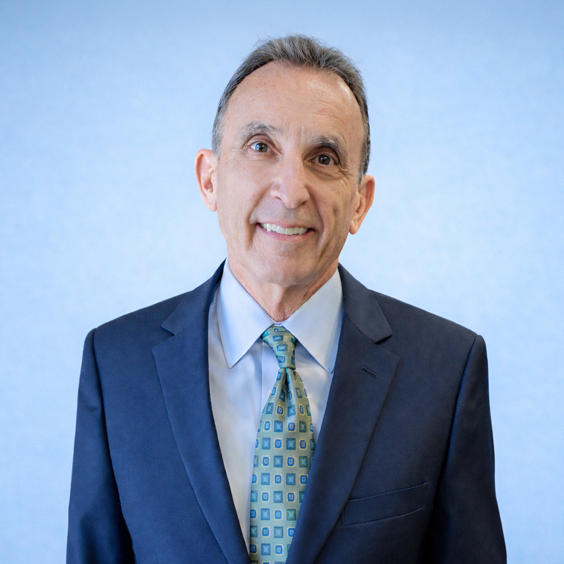 John Cassidy in suit against blue background