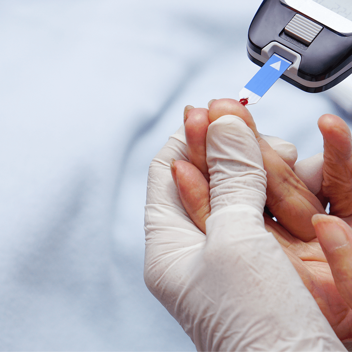 Doctor wear gloves is using lancet on a patient's finger